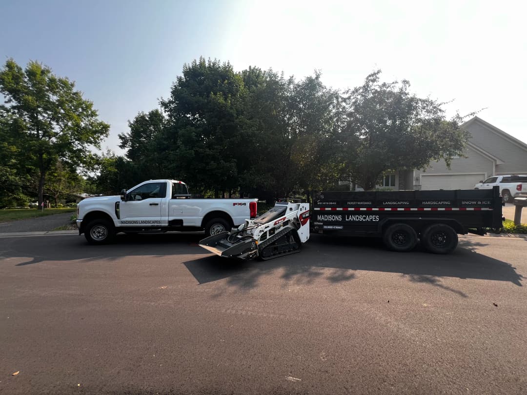 Madison's Landscapes truck and trailer with landscaping equipment parked on a residential street.