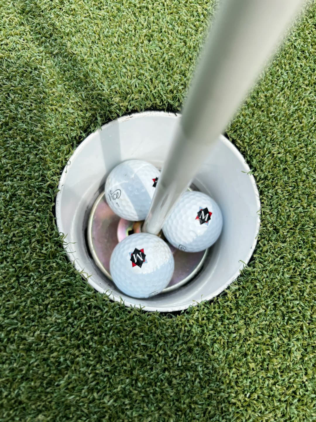 Golf balls in a hole on a putting green, showcasing successful shots and vibrant turf.