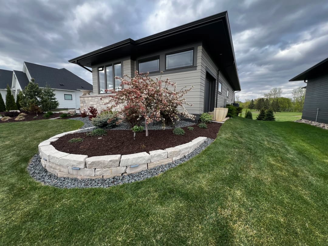 Modern home with landscaped garden featuring flowering tree and stone border.