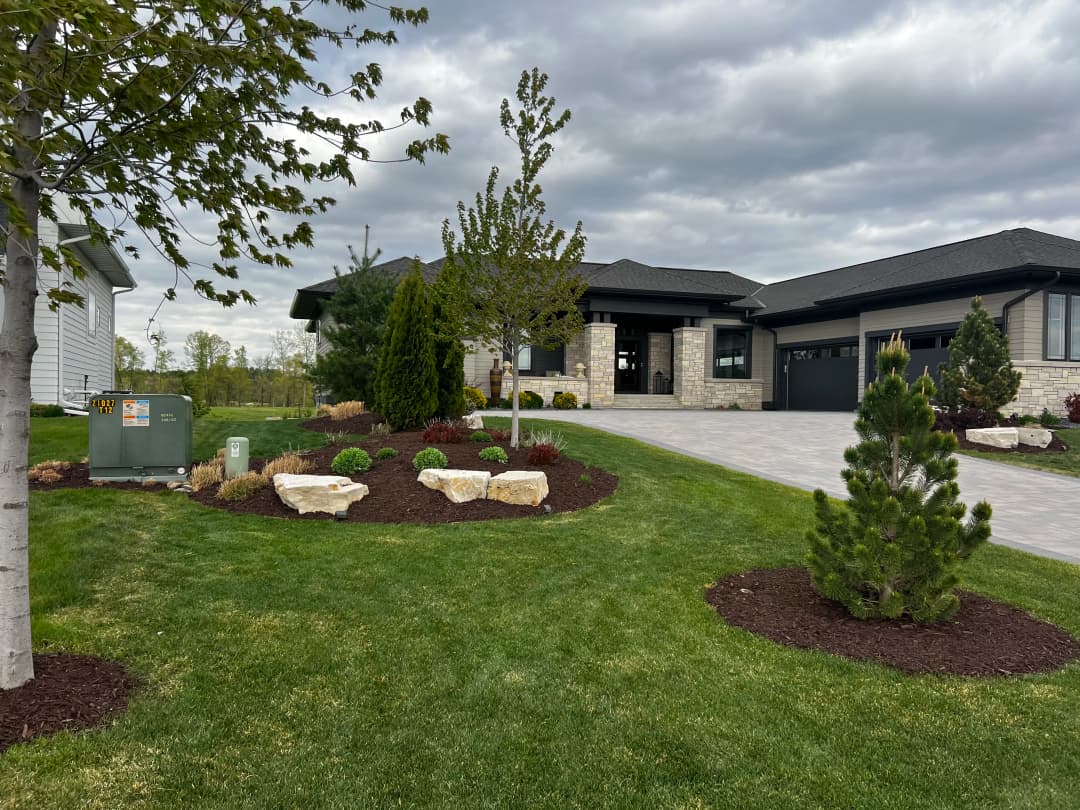 Modern home exterior with landscaped garden, stone accents, and paved driveway.