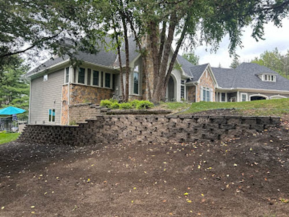 Modern home with stone landscaping and terraced garden on a sloped yard.