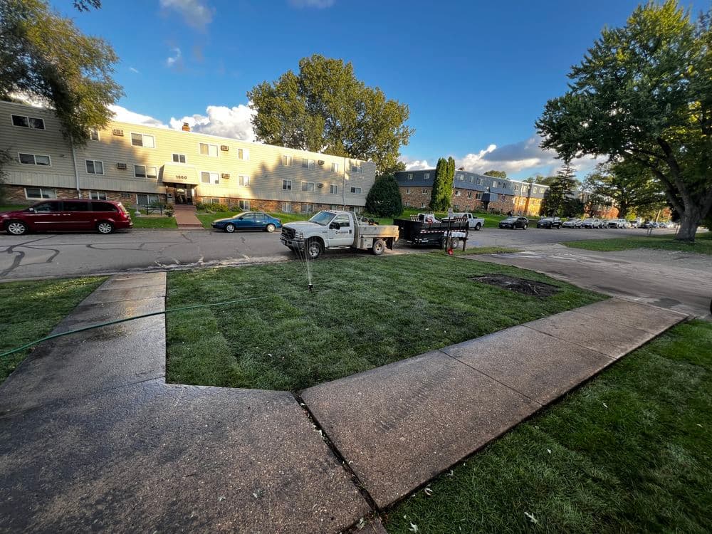 Pickup truck on a residential street beside freshly laid sod and paved walkway.