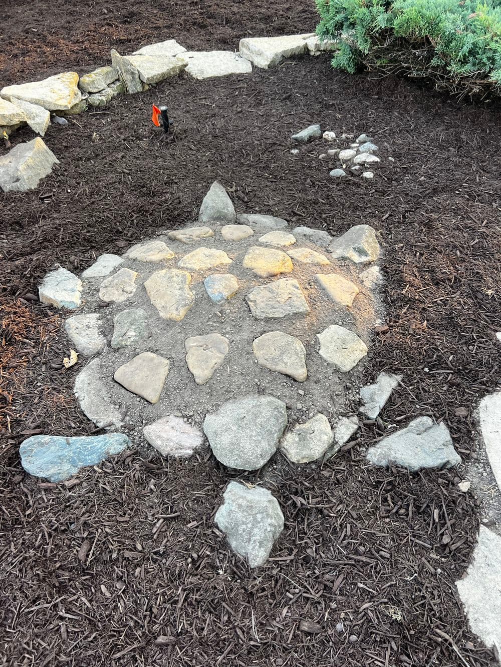 Stone turtle sculpture made of various rocks in a landscaped garden setting.