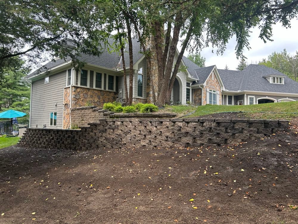 Modern home with stone accents, terraced landscaping, and lush greenery in the yard.